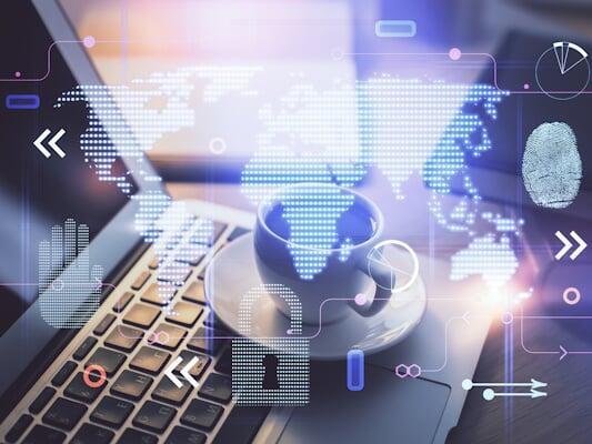 A laptop with a coffee cup, overlaid with digital security icons, including a world map, padlock, fingerprint, and data symbols, representing cybersecurity.